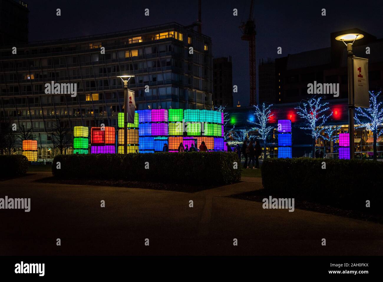 LIVERPOOL, in inghilterra, dicembre 27, 2018: sagome di persone aventi il divertimento di notte mentre in posa di fronte dei cubetti illuminato con luce diversa Foto Stock