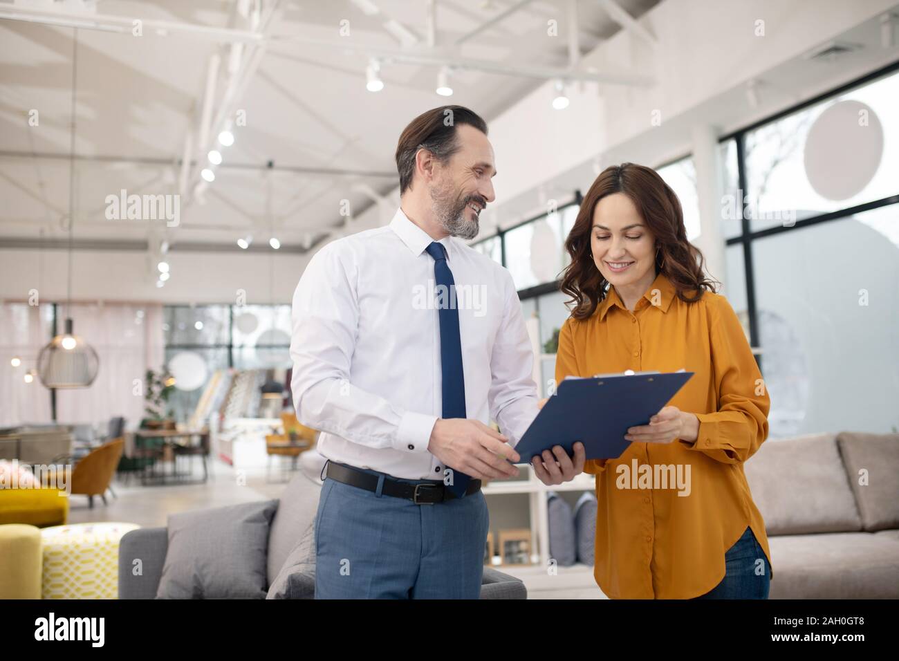 Consulente nel negozio di arredamento che mostra prezzo di listino al nuovo client Foto Stock