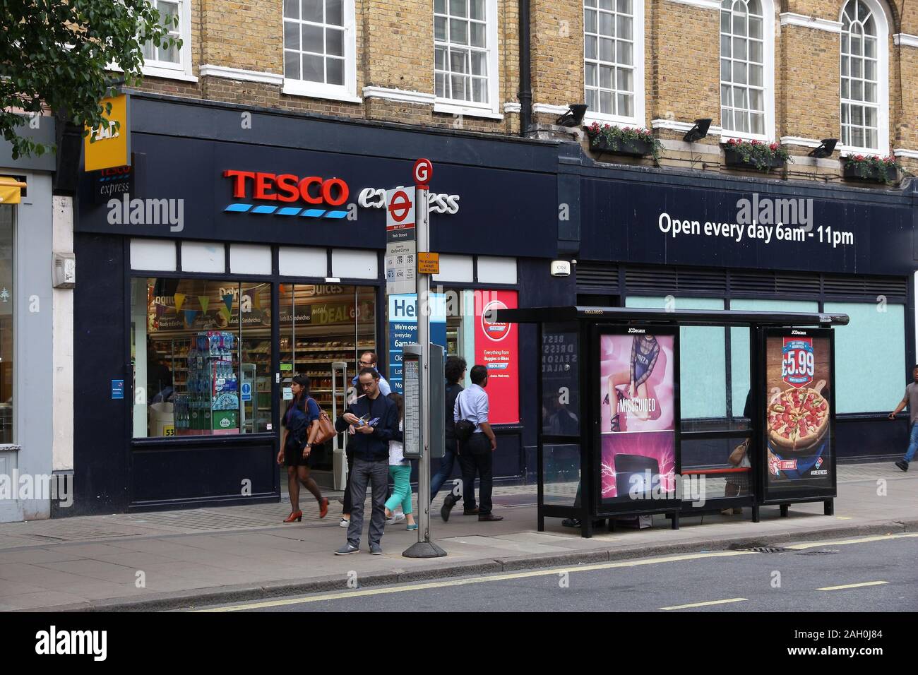 LONDON, Regno Unito - 7 Luglio 2016: la gente a piedi da Tesco Express drogheria a Londra. Tesco aveva 5.500 negozi come del 2017. Foto Stock
