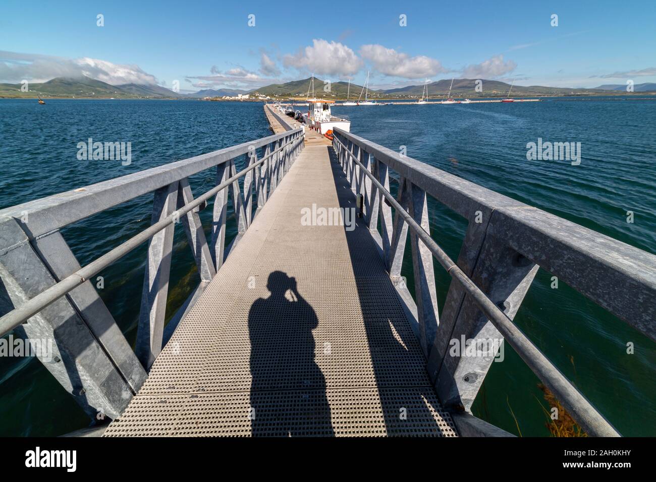Lunga ombra di un uomo con la fotocamera su metallo pontoon bridge, con obiettivo grandangolare. Foto Stock