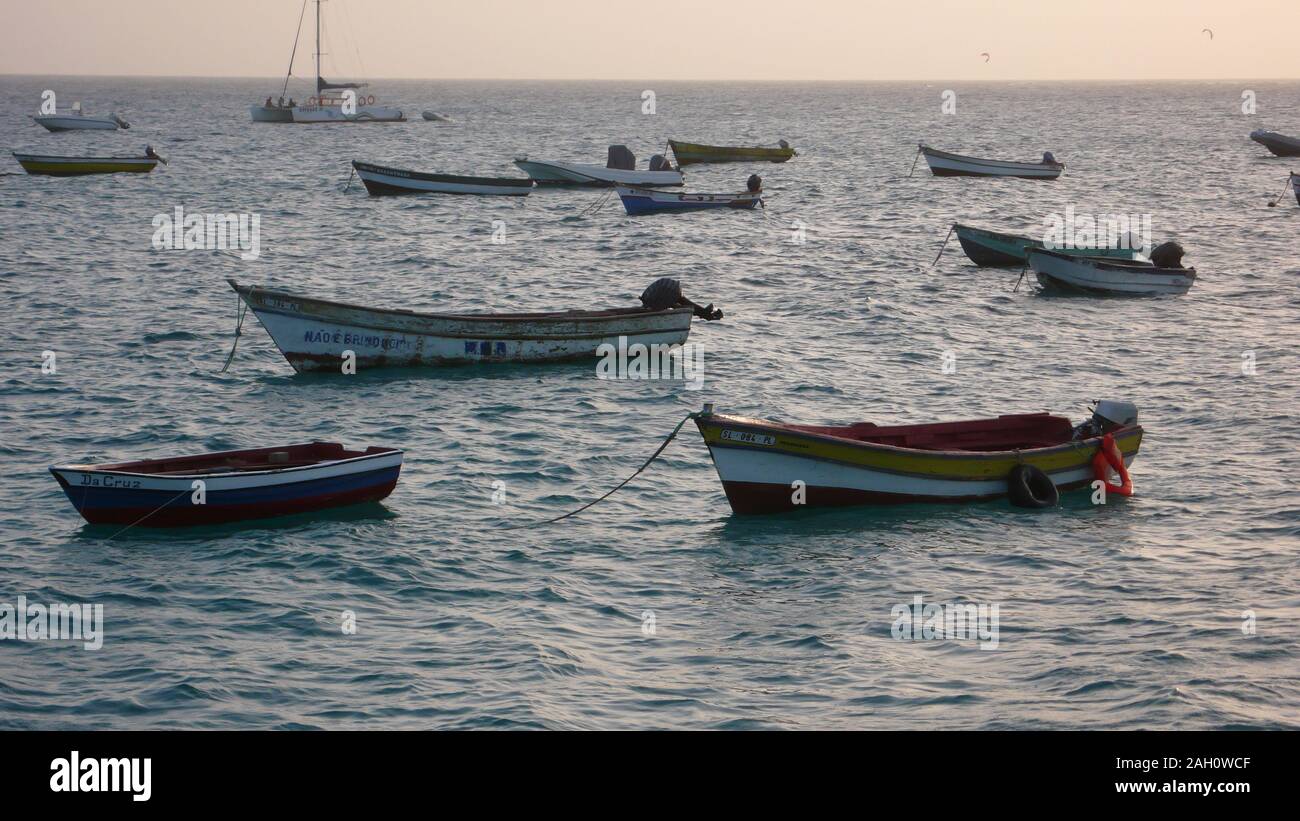 Punto di vista di molte piccole colorate barche da pesca e skiffs al di ancoraggio in un oceano di calma nel Capo Verde Isole sull isola di Sal Foto Stock