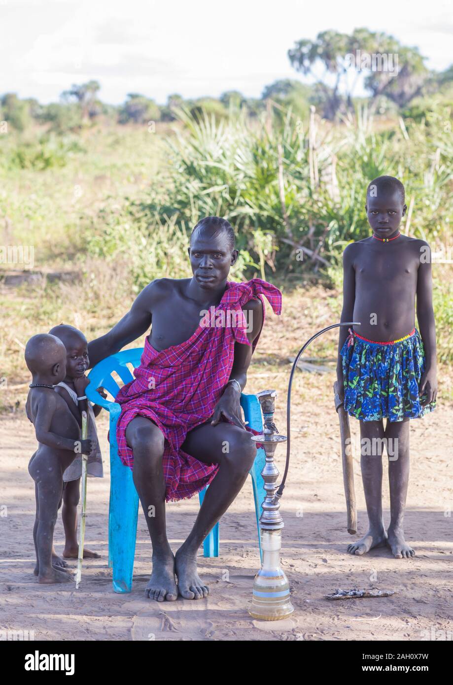 Tribù Mundari padre con i suoi figli di fumare shisha, Equatoria centrale, Terekeka, sud Sudan Foto Stock