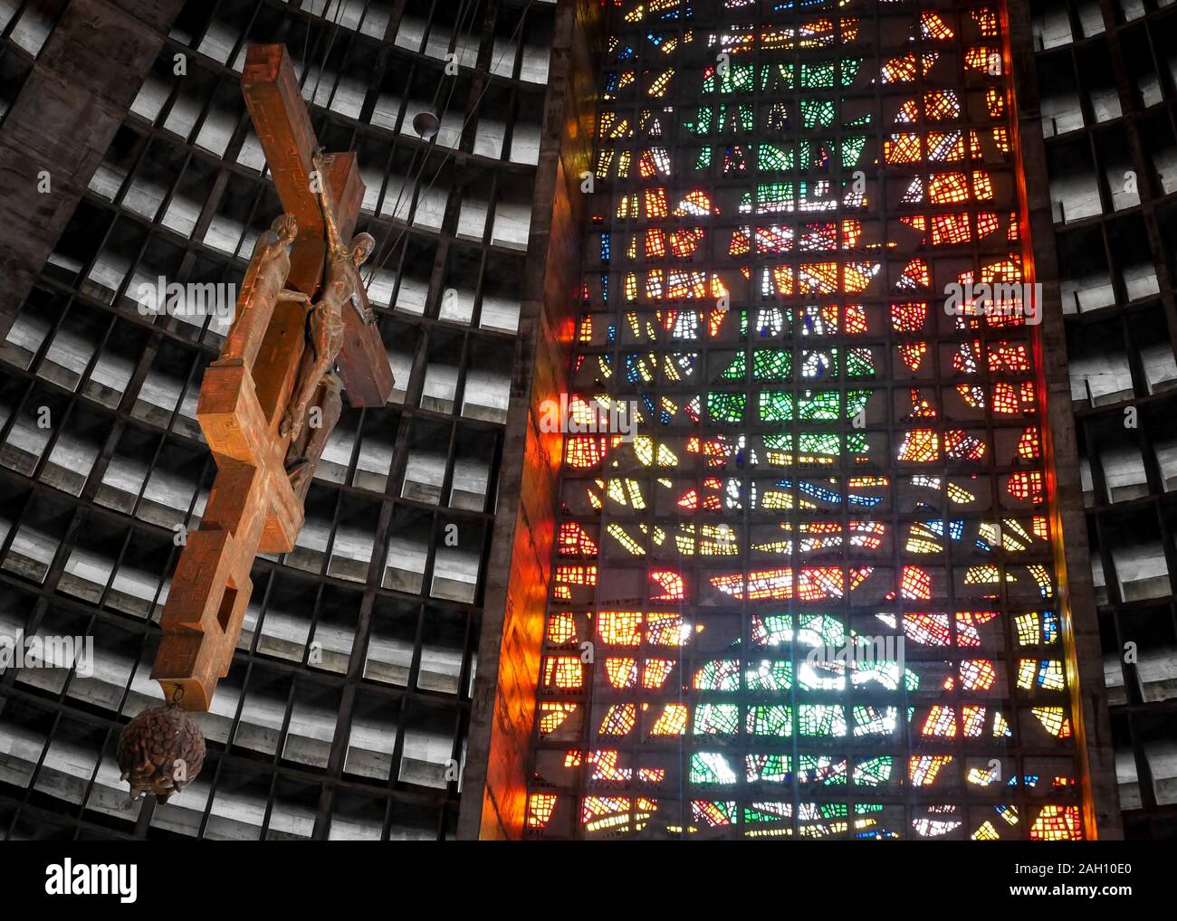 L'interno della Cattedrale di Rio con il suo crocifisso sospeso che contrasta con l'architettura brutalista e le vetrate colorate. Foto Stock