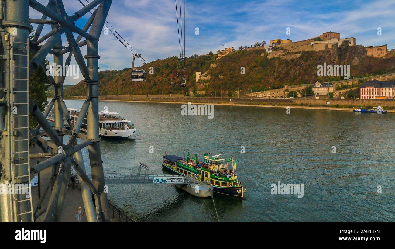 Bella vista della fortezza Ehrenbreitstein sulla riva orientale del Reno, le navi passeggeri sull'acqua e la funivia di attraversare il fiume su un... Foto Stock