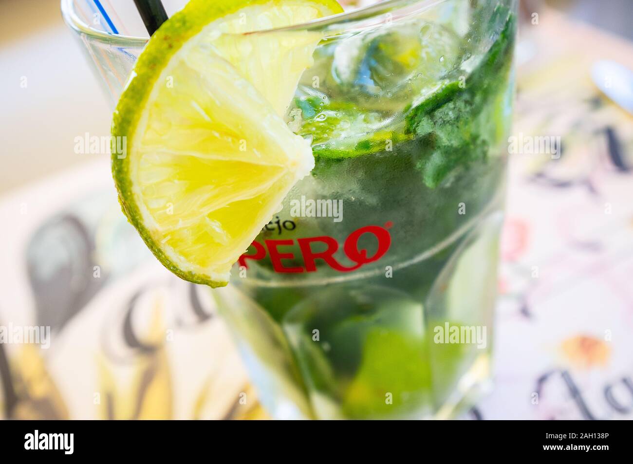 Primo piano di un pezzo di calce su un cocktail in un bicchiere su un tavolo Foto Stock