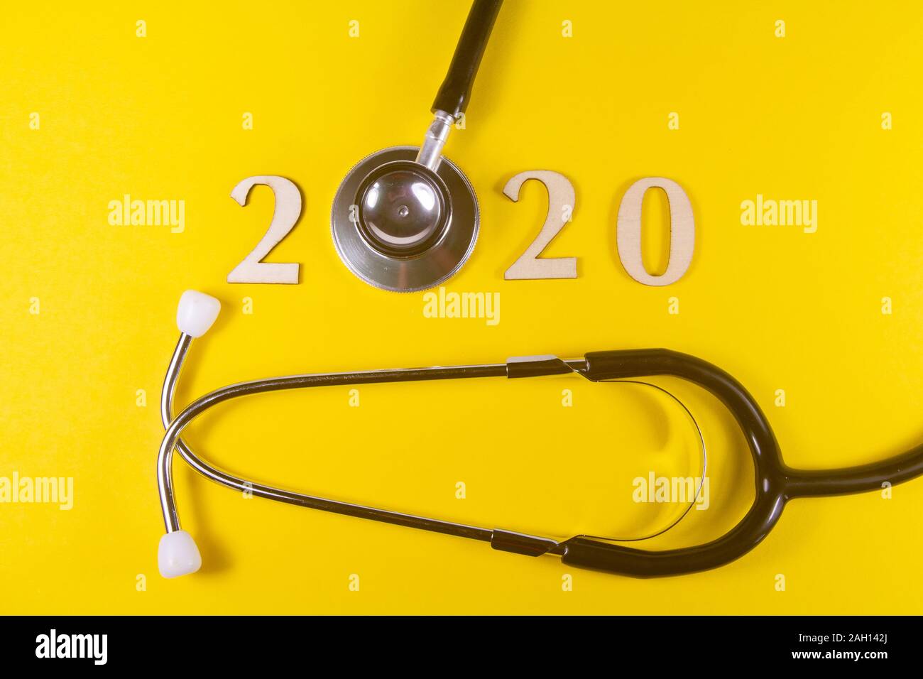 2020 Nelle Figure in legno e stetoscopio nero su sfondo giallo Foto Stock