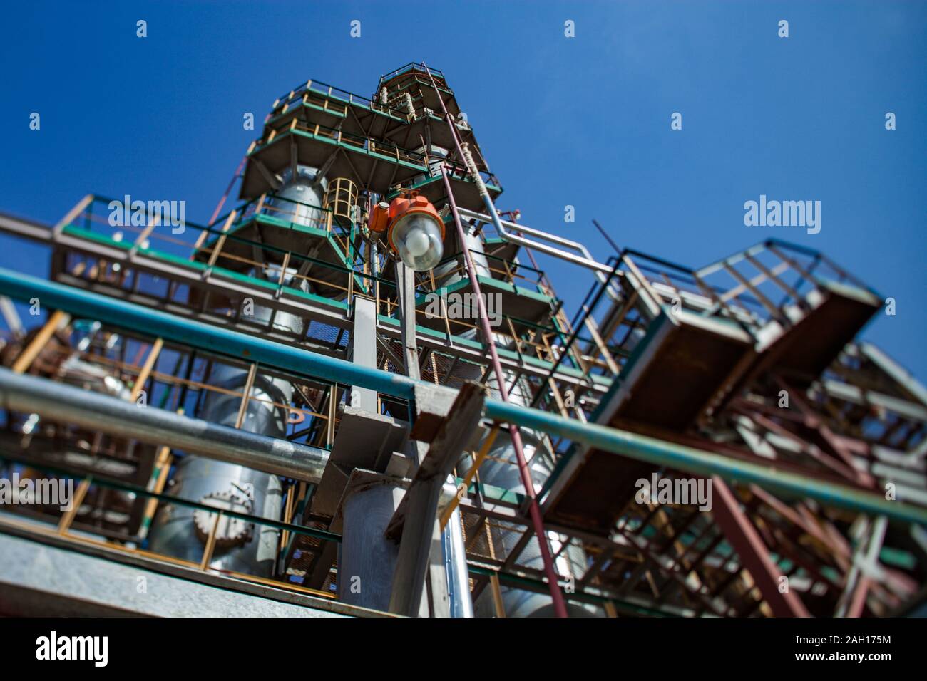 Grigio di raffinazione di olio di colonne e tubazioni sull'olio impianto di lavorazione su un profondo cielo blu. Foto Stock