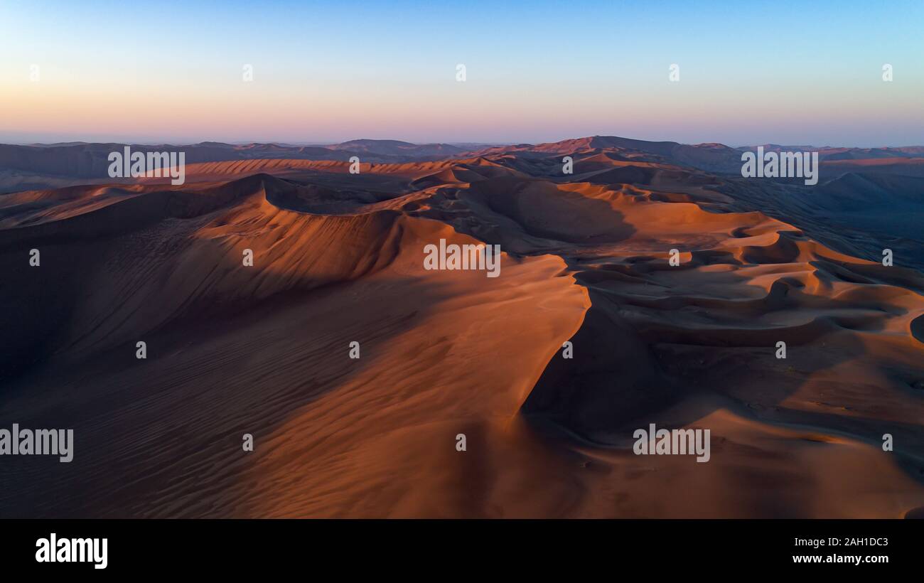 Vista aerea dalla formazione di alte dune di sabbia e profonde valli con cielo limpido all'alba nel deserto di dasht e LUT Foto Stock