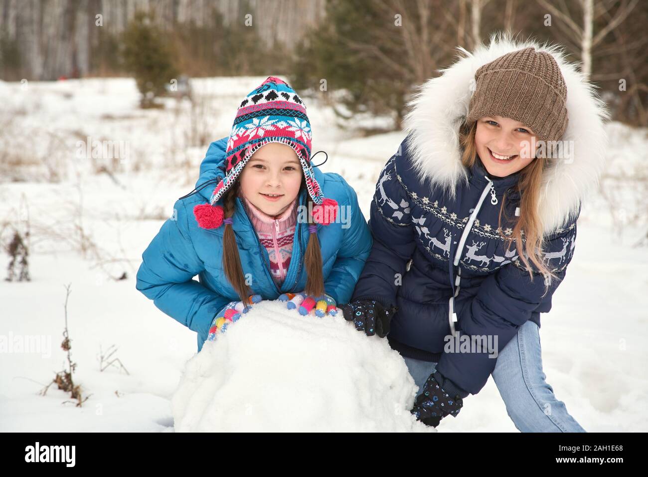 due amici femminili che costruiscono un pupazzo di neve. ragazze divertenti su una passeggiata in inverno all'aperto. Foto Stock