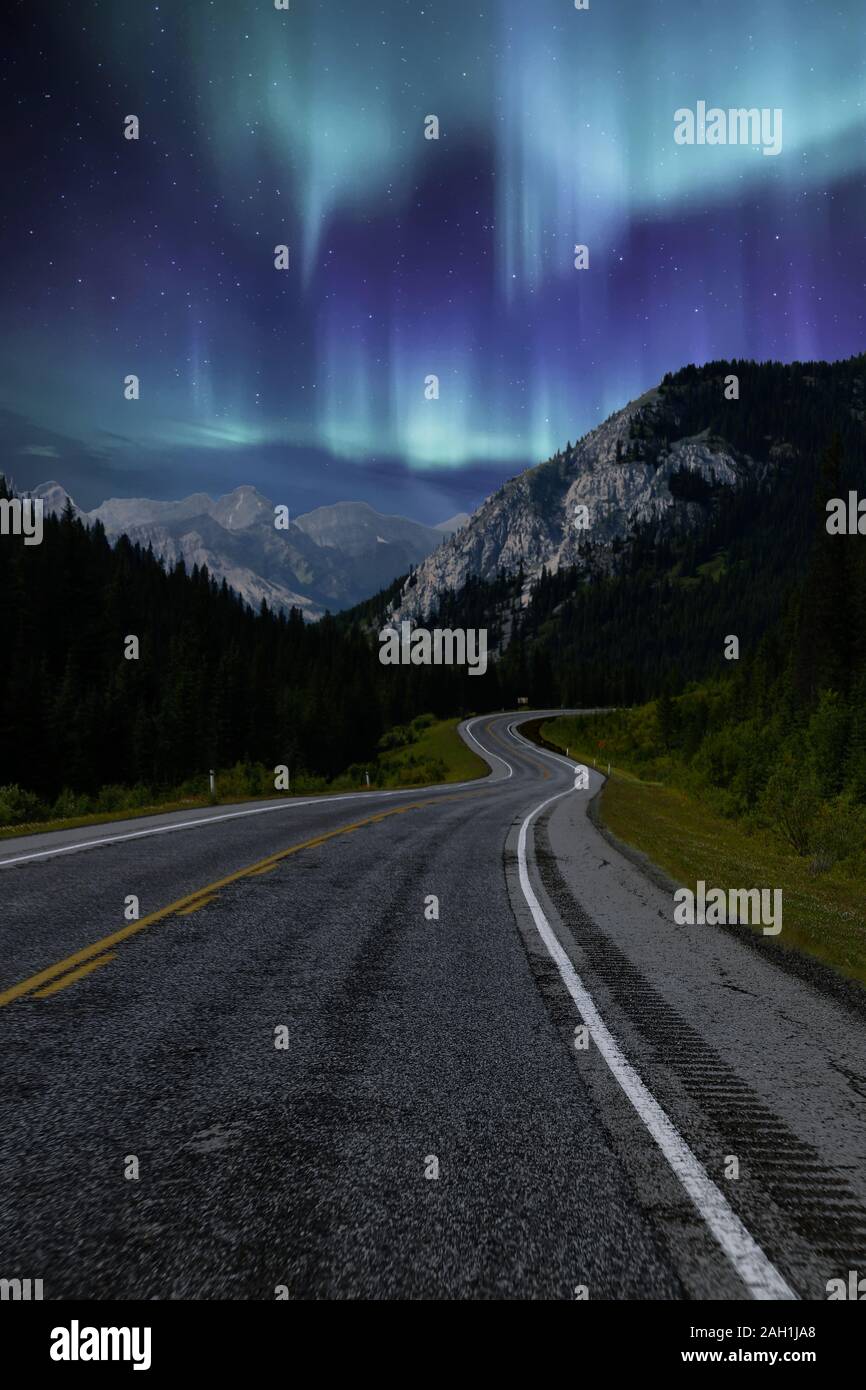 Diving lungo la strada di notte con luci del nord nel cielo, Alberta, Canada Foto Stock