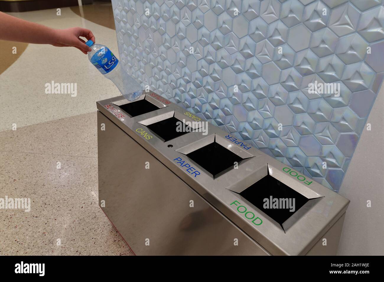 Doha, Qatar - Nov 20. 2019. La mano dei bambini mette una bottiglia di plastica in un contenitore separato nella stazione della metropolitana di al bidda Foto Stock