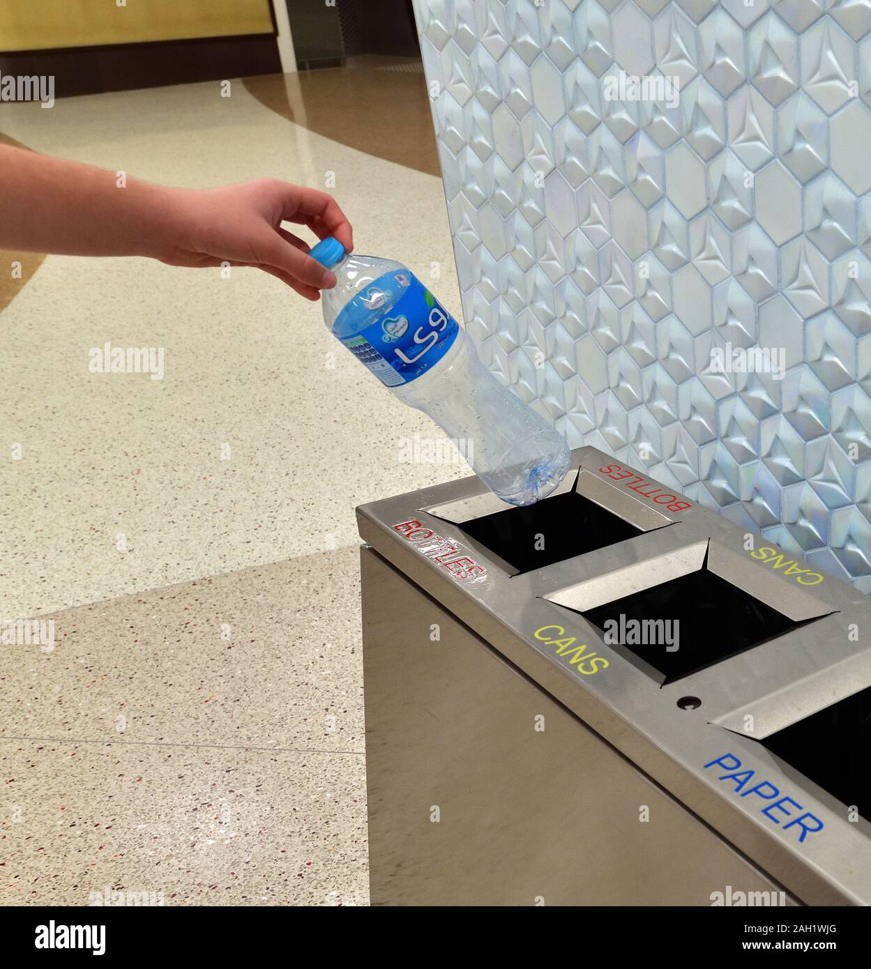 Doha, Qatar - Nov 20. 2019. La mano dei bambini mette una bottiglia di plastica in un contenitore separato nella stazione della metropolitana di al bidda Foto Stock