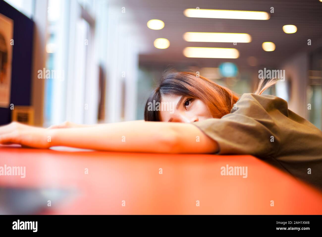 Lonely ragazza triste in attesa di qualcuno e giacente sulla tabella rossa Foto Stock