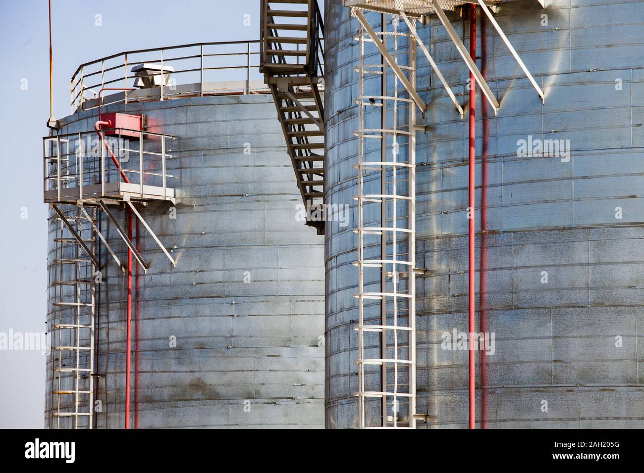 Close-up di zincatura o in acciaio serbatoi in metallo su un cielo grigio sulla raffineria di petrolio vegetale o impianto di trattamento di gas. Foto Stock