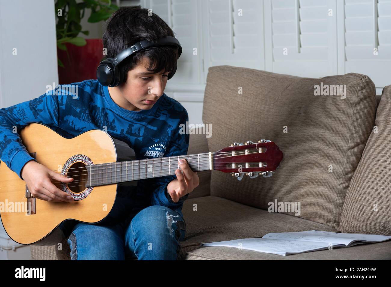 Ragazzo adolescente suona la chitarra acustica Foto Stock