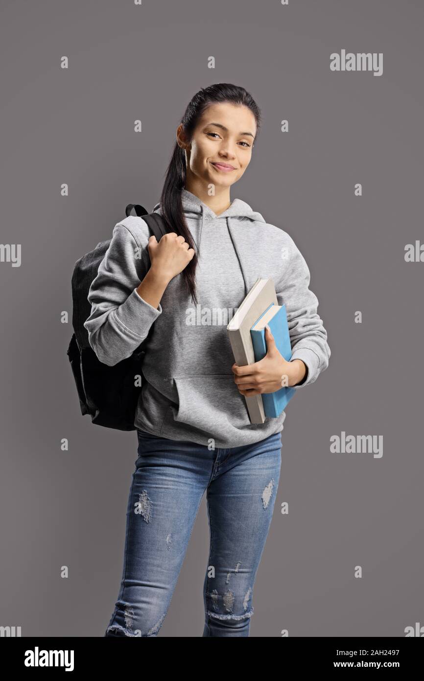 Studentessa con uno zaino e libri su uno sfondo grigio Foto Stock