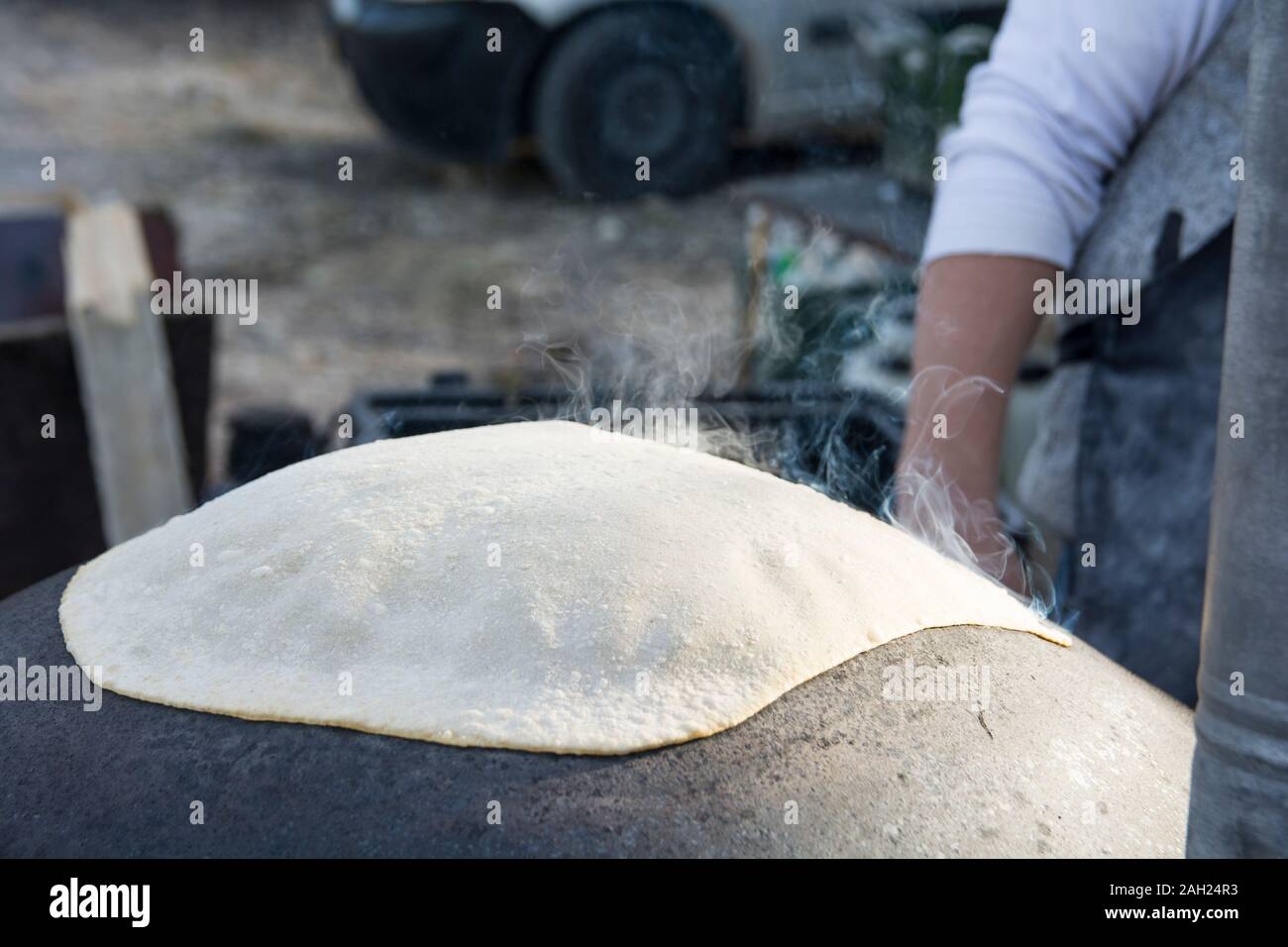 L'uomo la cottura di un tradizionale Drusi Pane Pita, su un Saj o Tava Foto Stock