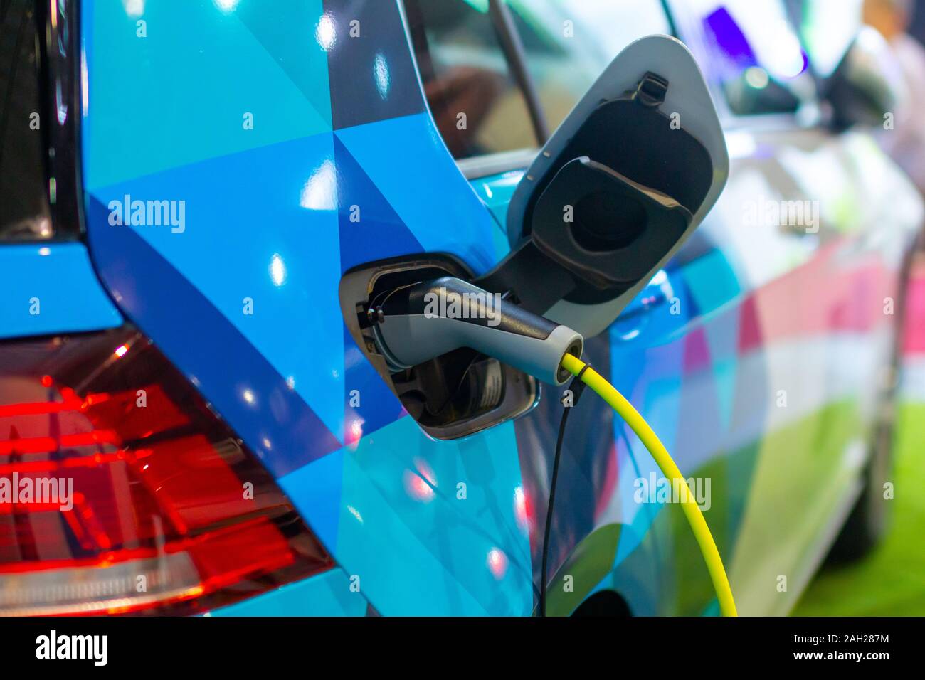 La ricarica di una o ibridi elettrici PHEV auto con la potenza di alimentazione del cavo collegato alla presa di corrente. Auto elettrica della stazione di carica Foto Stock