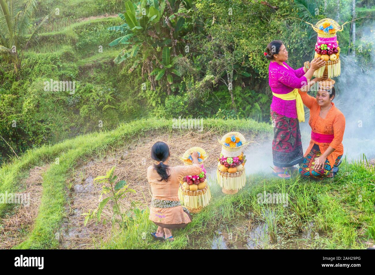 Ubud, Bali - Luglio 29, 2016: i tradizionali abiti cerimoniali di donna balinese e i loro cestini alti del tempio indù offerte di cibo. Foto Stock