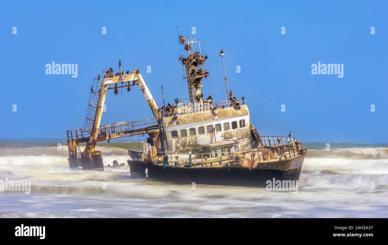 Una lunga esposizione inquadratura di un peschereccio naufragato sullo scheletro Costa della Namibia, coperto di uccelli nidificanti. Foto Stock