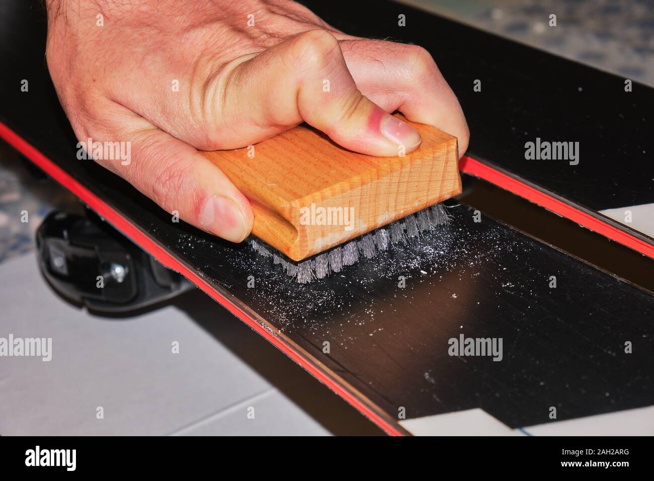 Mano maschio utilizzando un acciaio inossidabile spazzola per pulire e aprire la struttura di una base di sci. Sintonizzazione di sci e lo strumento di manutenzione. Foto Stock