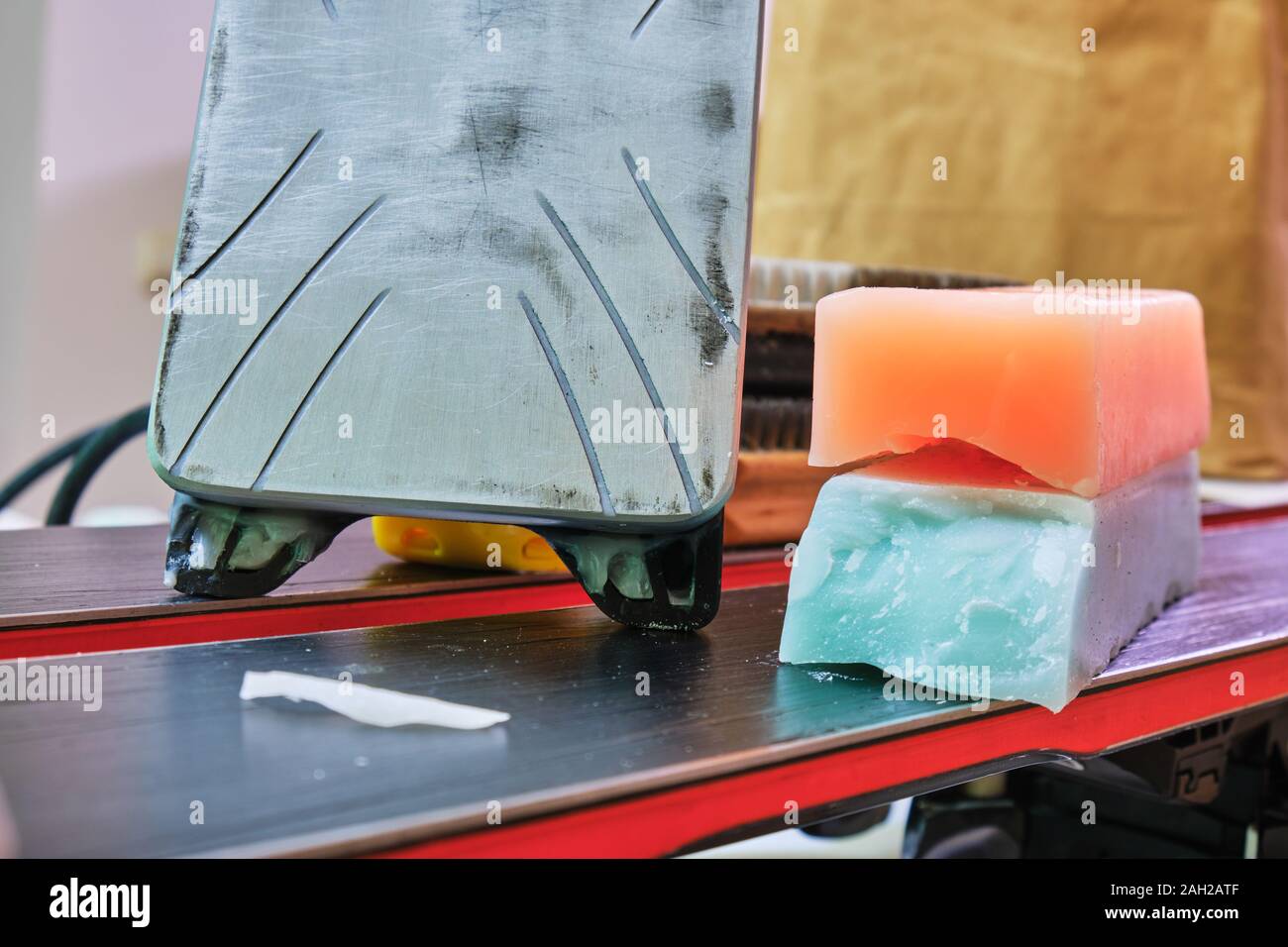 Sci wax ferro e barre di cera, colorato di arancione e teal per diverse temperature previste sulla parte superiore di un paio di sci. Sci di base il concetto di sintonizzazione. Foto Stock