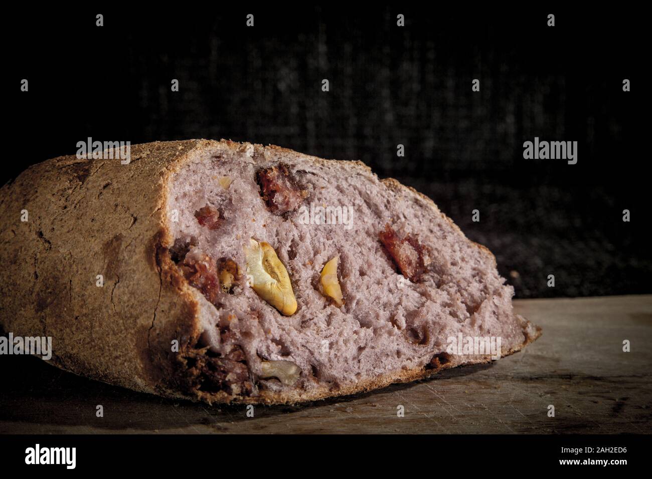 Il vino aromatizzato (pane pain au vin) con il suo tipico colore rosso all'interno, farcito con noci, sul display su un asse di legno. Si tratta di un tipico francese antico snack. Foto Stock