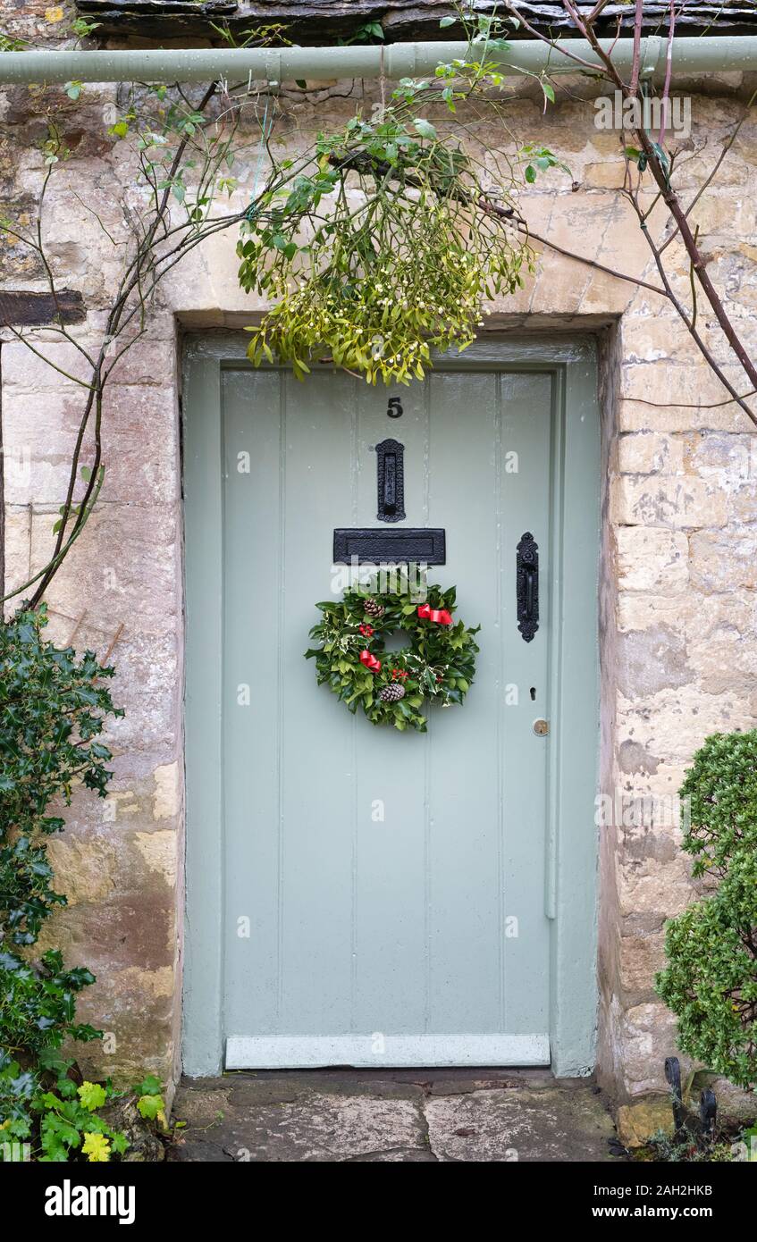 Natale ghirlanda di agrifoglio e vischio su un cottage porta ad Arlington in fila. Bibury, Cotswolds, Gloucestershire, Inghilterra Foto Stock