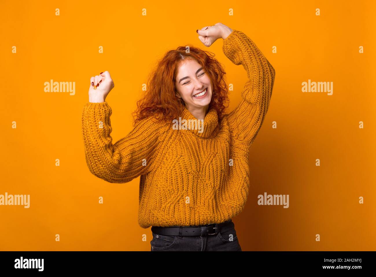 Foto di zenzero giovane donna, divertendosi e celebrazione con fatto alzare le mani, su sfondo isolato Foto Stock