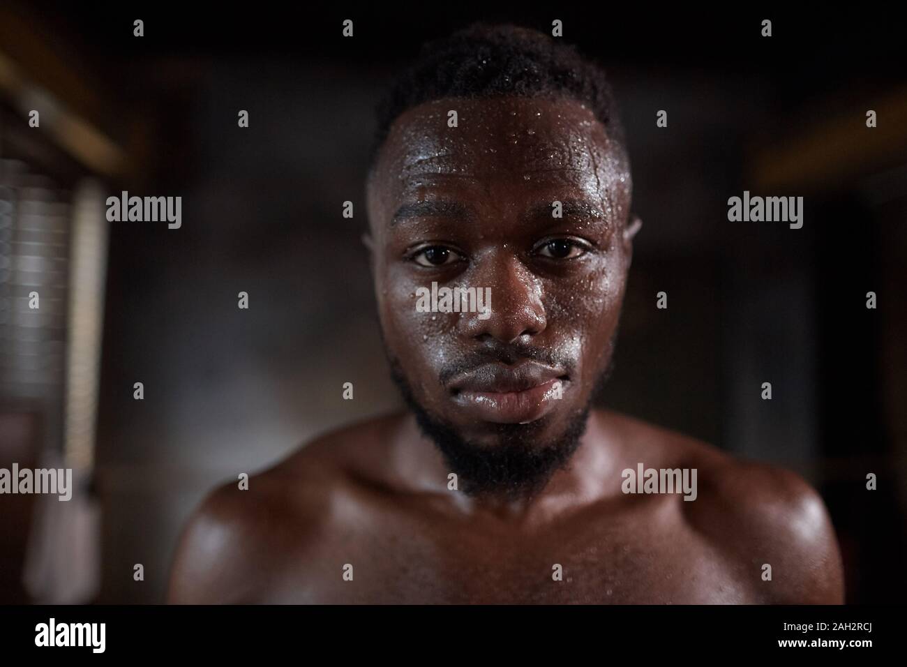 Ritratto di giovane africano shirtless sportivo guardando la fotocamera durante gli allenamenti in palestra Foto Stock