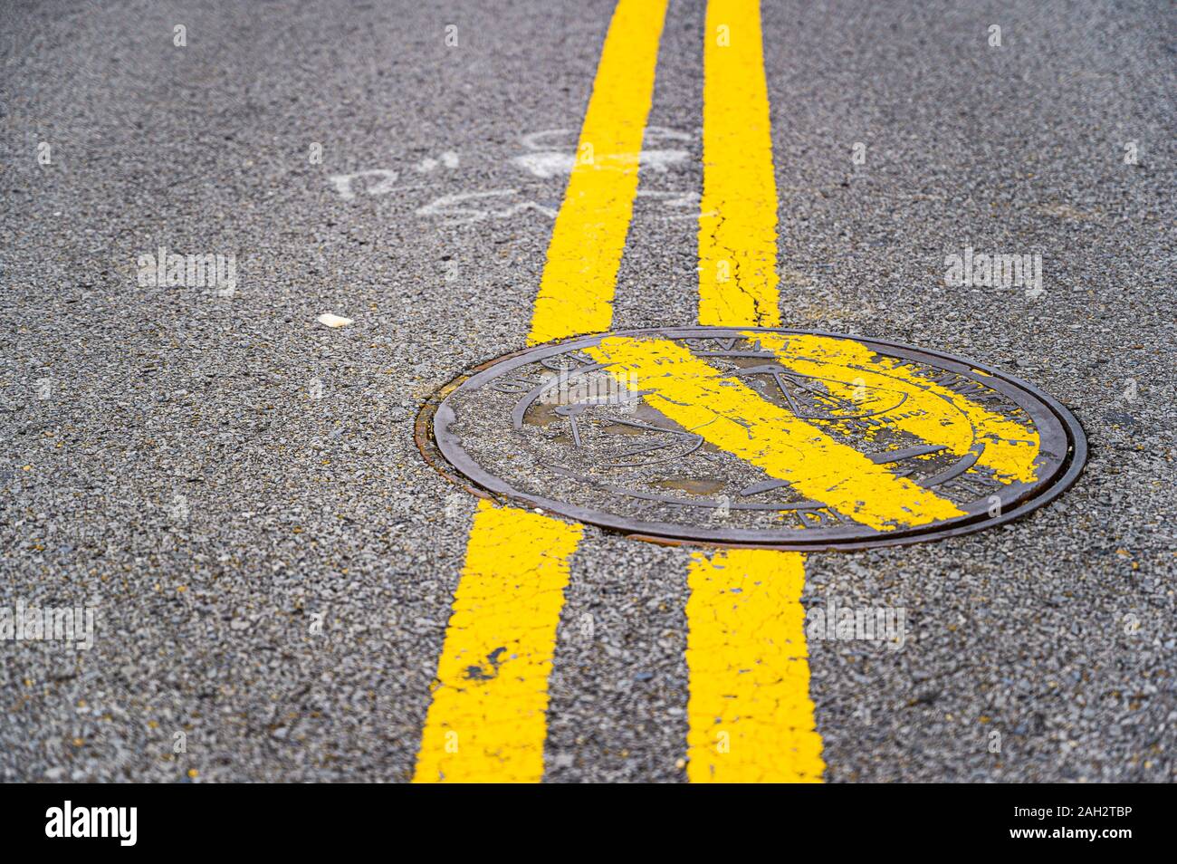 Doppie linee gialla dipinta su un chiusino di divertente effetto. Foto Stock