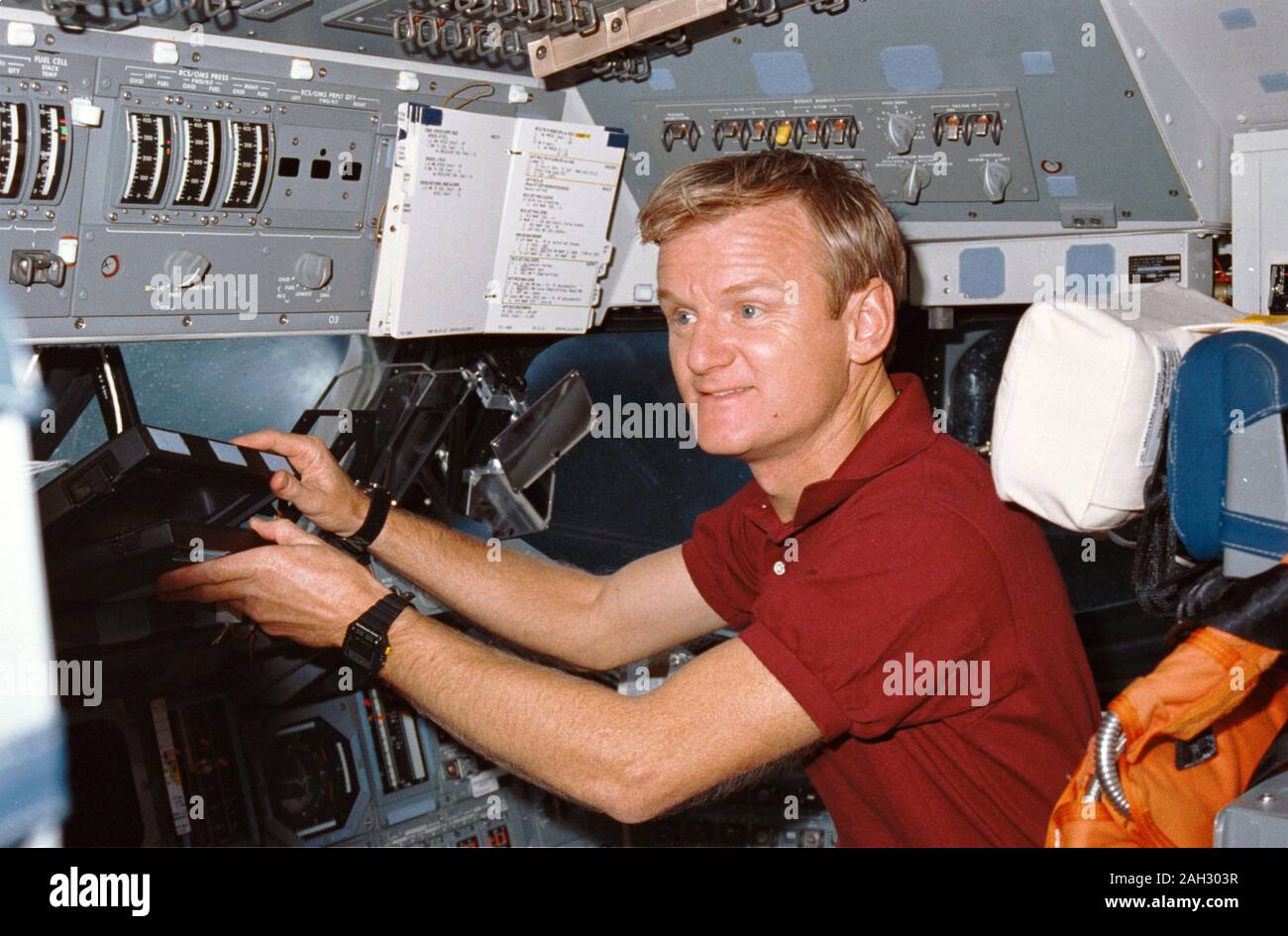 STS-36 pilota Giovanni H. Casper raggiunge per la navetta portatile computer di bordo (SPOC), un computer portatile, mentre presso la stazione di piloti sulla fuga in avanti mazzo di Atlantis, Orbiter veicolo (OV) 104. Casper, seduto nel sedile del pilota, solleva la SPOC dalla finestra di avanzamento battuta. Che compaiono intorno a lui sono avanti vano equipaggio windows, head up display (HUD), il volo complessivo specchietto, e una checklist allegata al pannello di controllo O3. Foto Stock