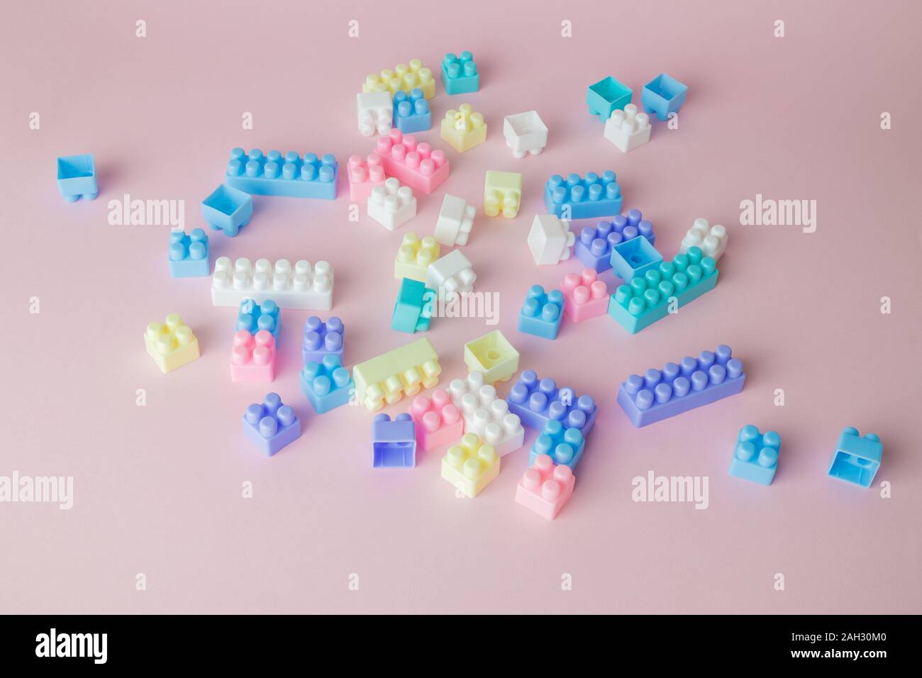 In plastica blocchi di costruzione giocattolo sul rosa pastello minima di sfondo concetto creativo. Foto Stock