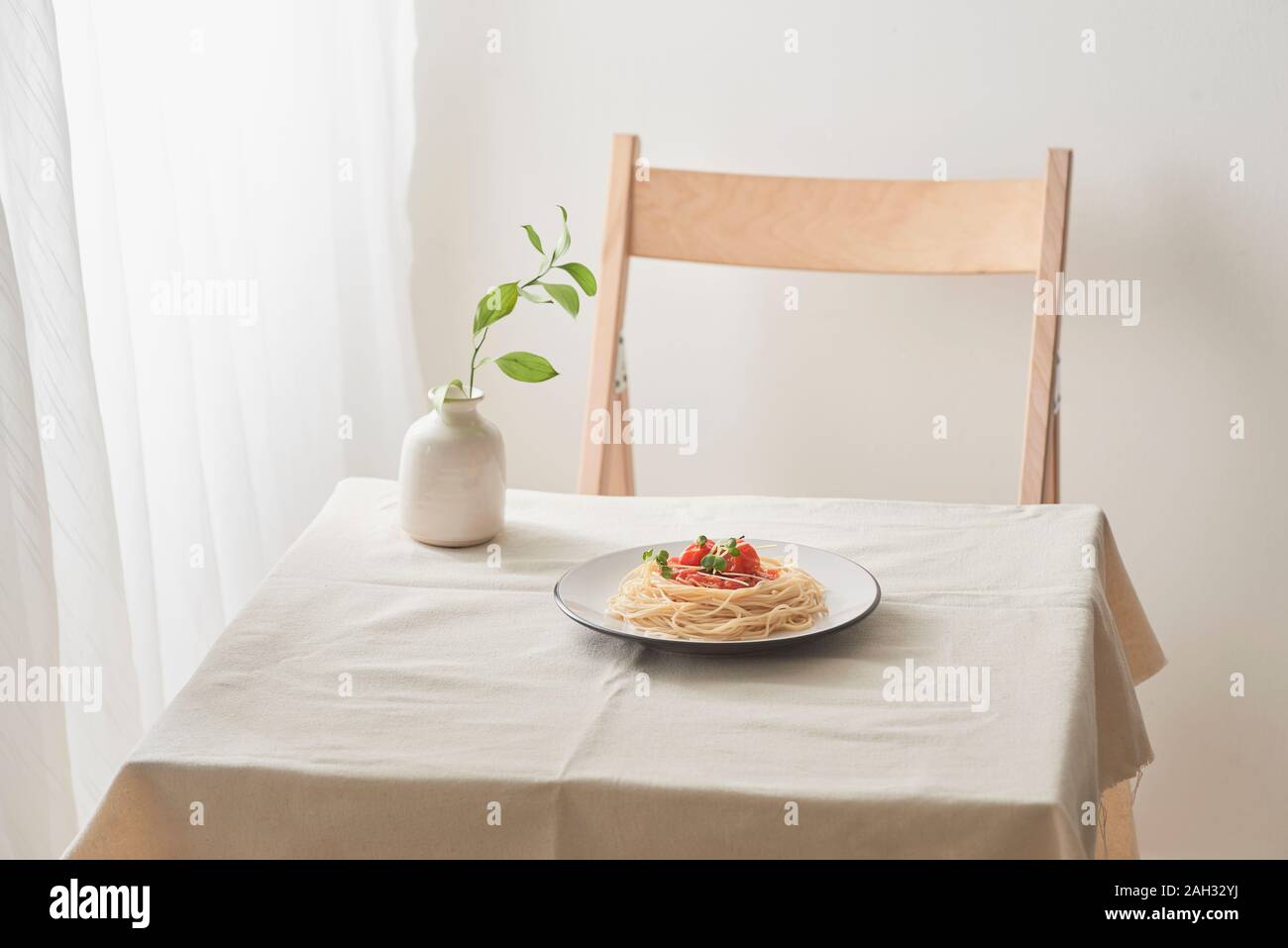 La pasta fatta a mano con sugo di ragù sulla piastra su vintage white tavolo con scolapasta e fiori Foto Stock