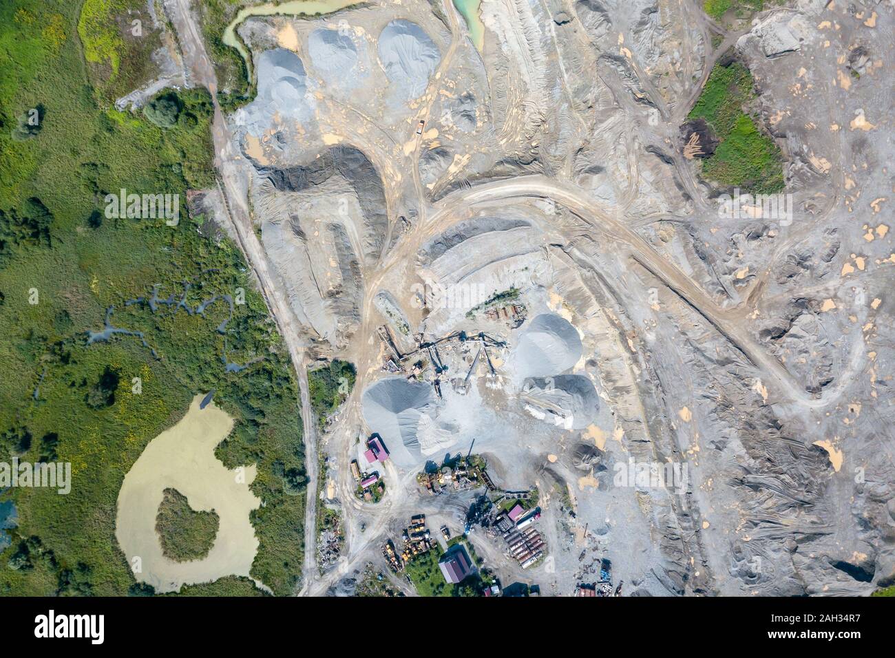 Vista aerea di un piccolo impianto per la produzione e la pulizia di macerie e cemento vicino a cumuli di materiali da costruzione, i trattori camion e trasporto Foto Stock