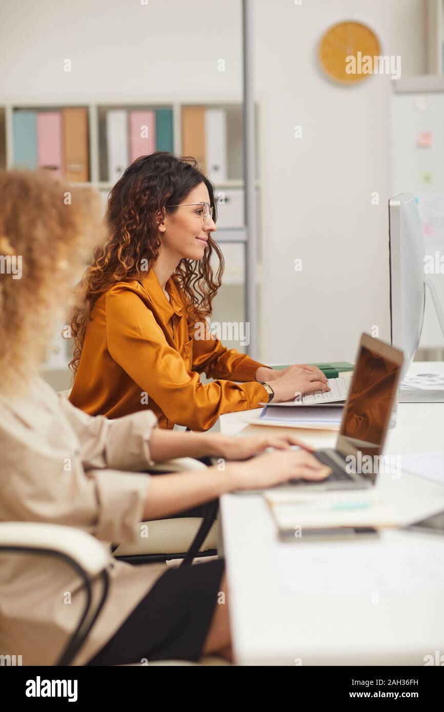 Le donne che lavorano su computer in ufficio moderno verticale vista laterale shot Foto Stock