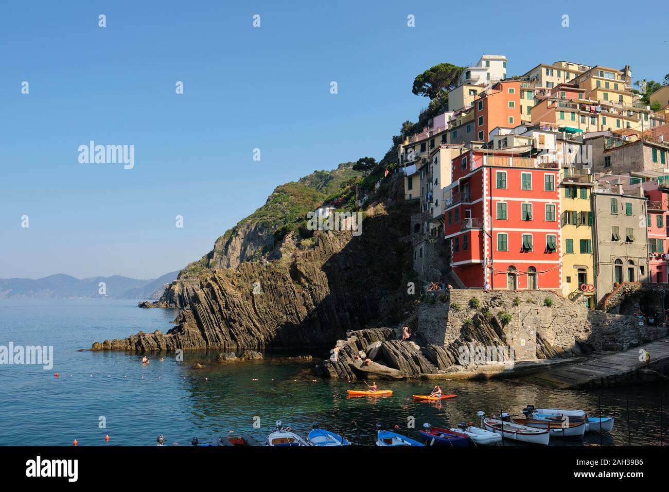 Kayakers e le case dipinte e architettura della scogliera porto di Riomaggiore village, il Parco Nazionale delle Cinque Terre Liguria Italia EU Foto Stock