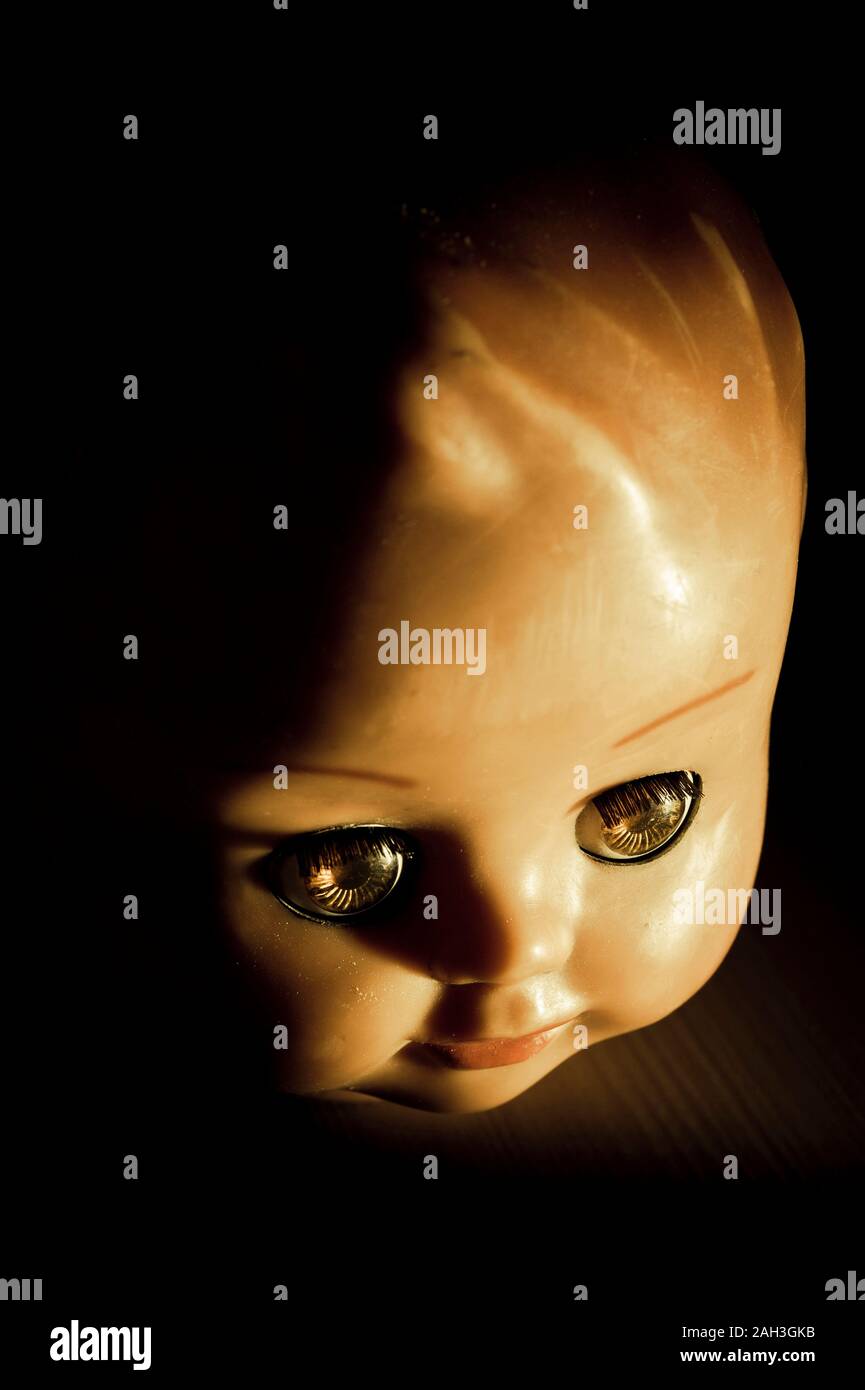 Spooky testa di bambola in luce drammatica Foto Stock