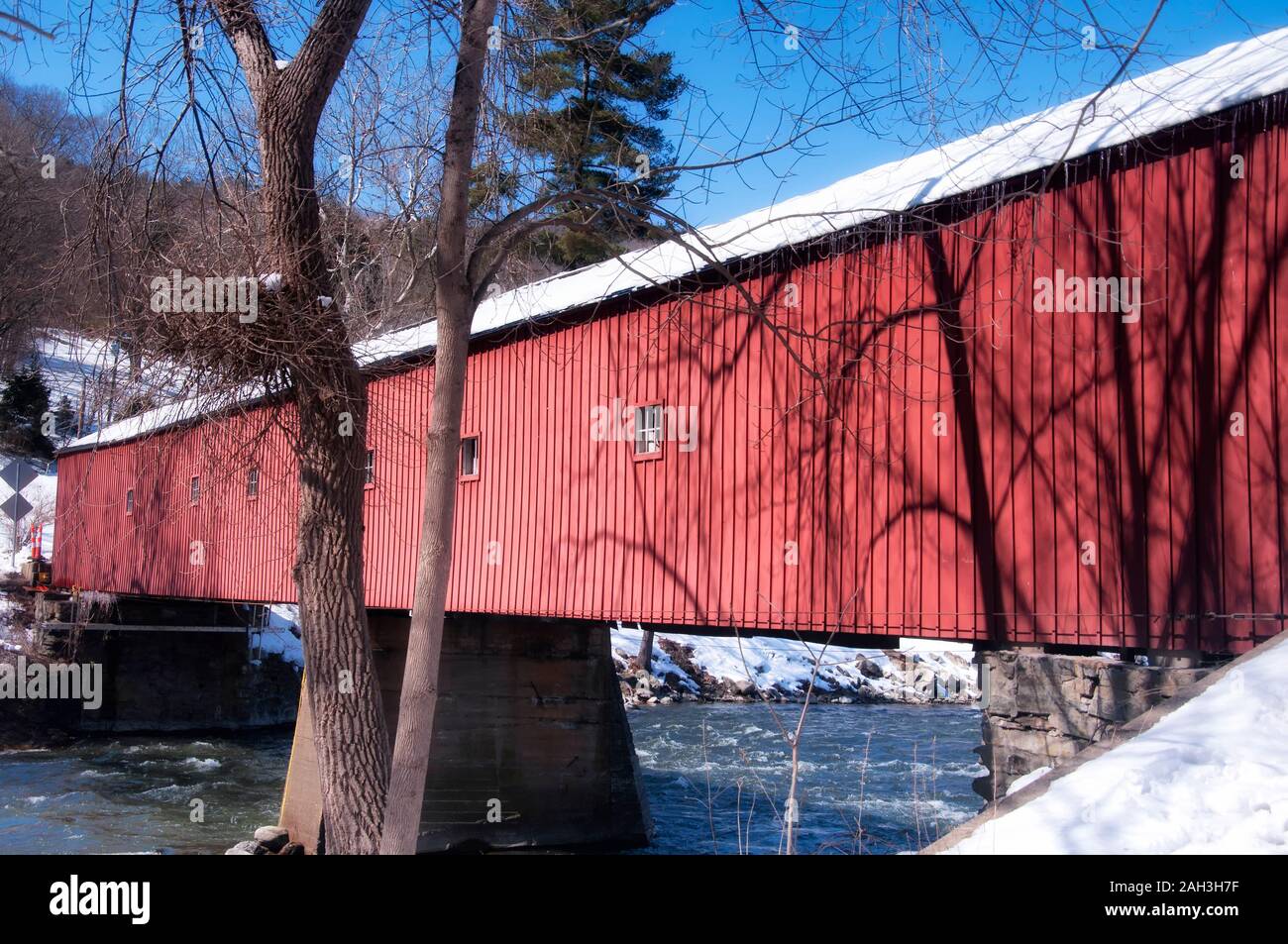 La coperta di neve landmark west cornwall coperto ponte che attraversa il fiume Housatonic su una soleggiata giornata invernale nel Connecticut. Foto Stock