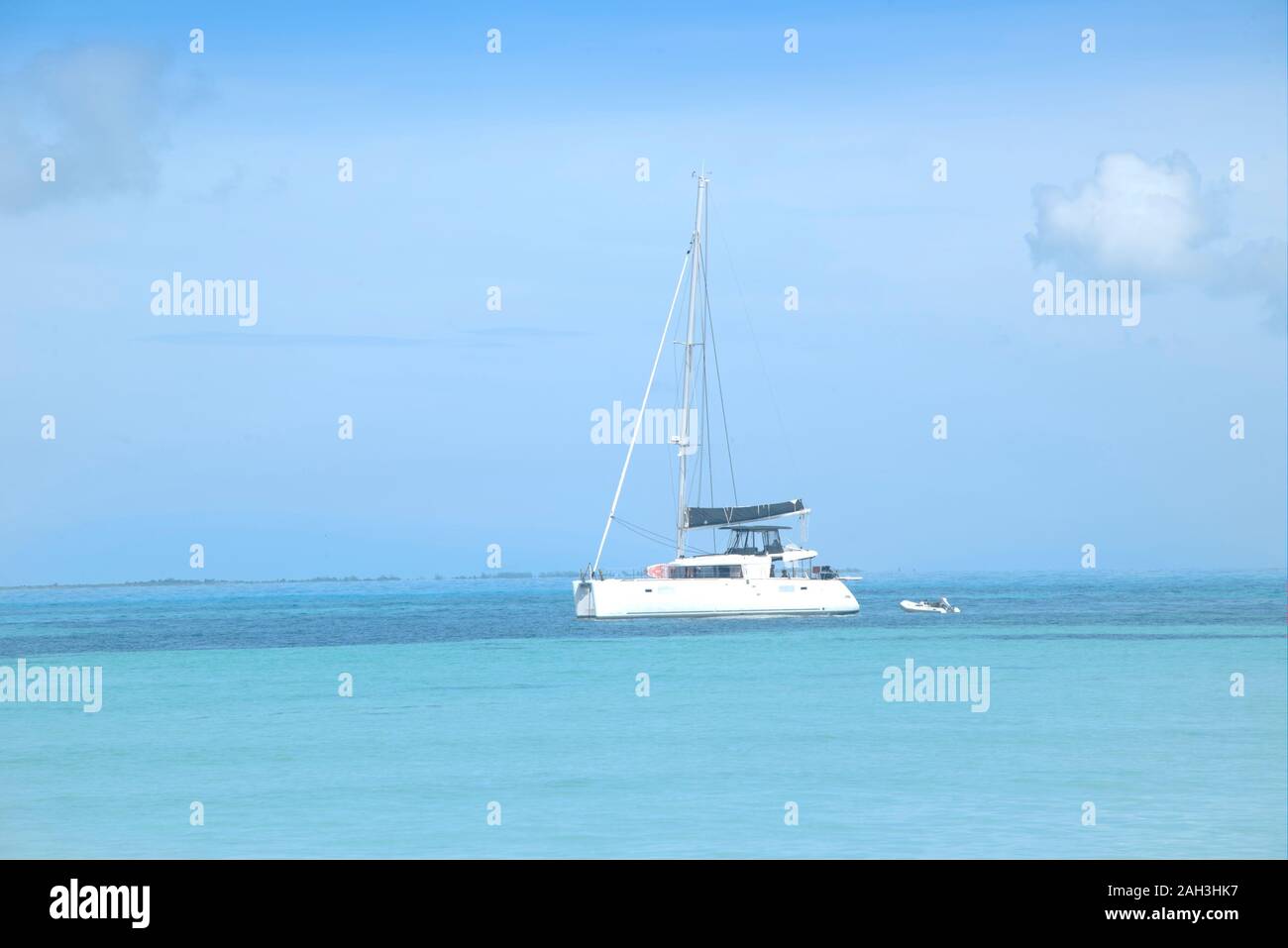 Lussuoso catamarano di fronte a dei Caraibi spiaggia bianca. Le persone felici giocare e nuotare nel mare calmo vicino al yacht Foto Stock