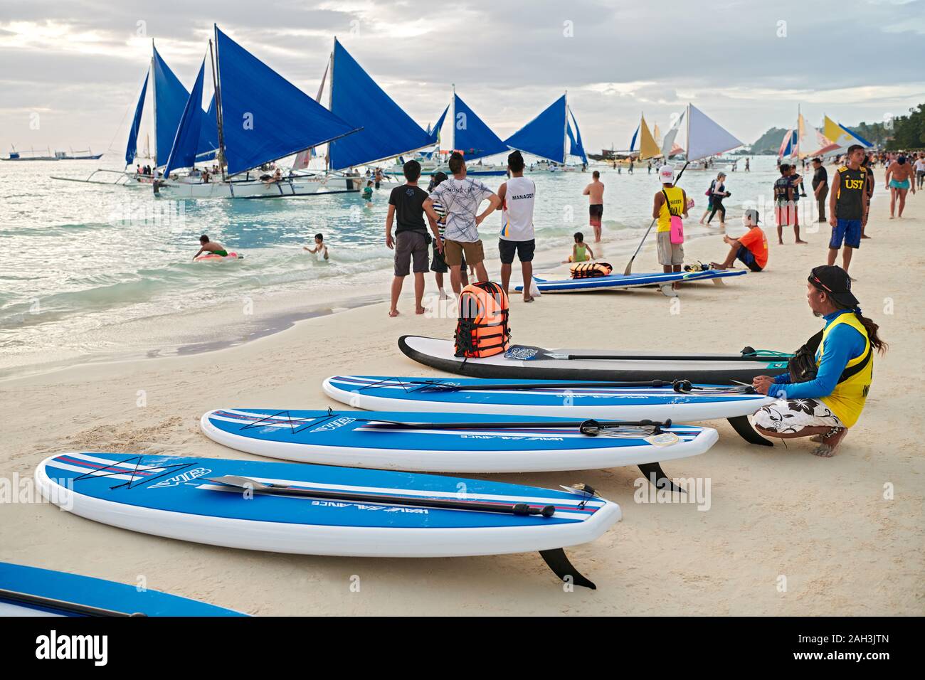 Il Boracay, Aklan Provincia, Filippine - 6 Gennaio 2018: Tramonto scenario della spiaggia bianca con paddle boards e barche a vela in attesa per i turisti Foto Stock