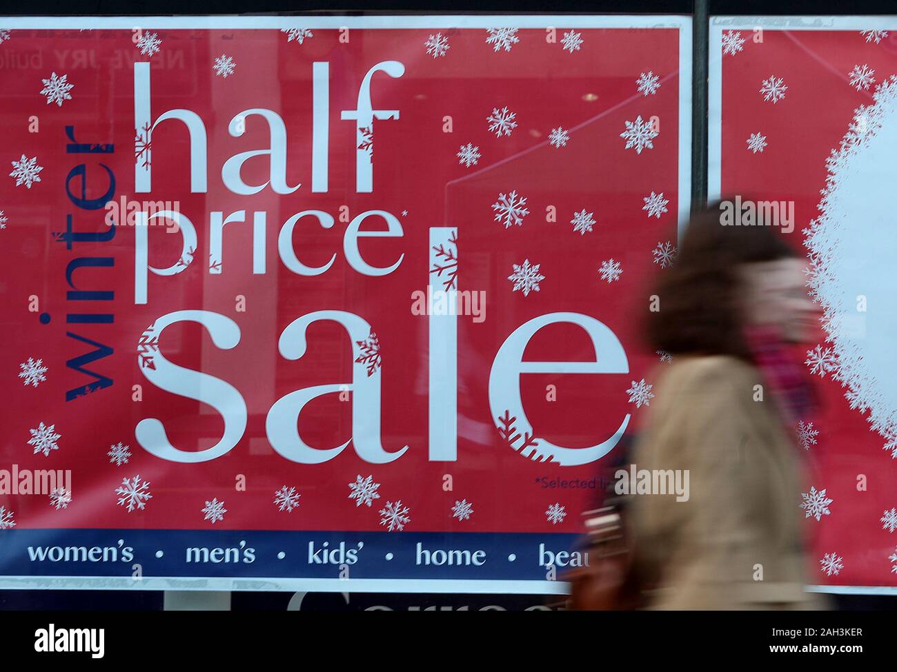 Gli acquirenti di Natale a piedi passato un segno di vendita nella finestra di Debenhams su Winchester High Street, negozi come prepararsi per il boxing day vendite. Foto Stock