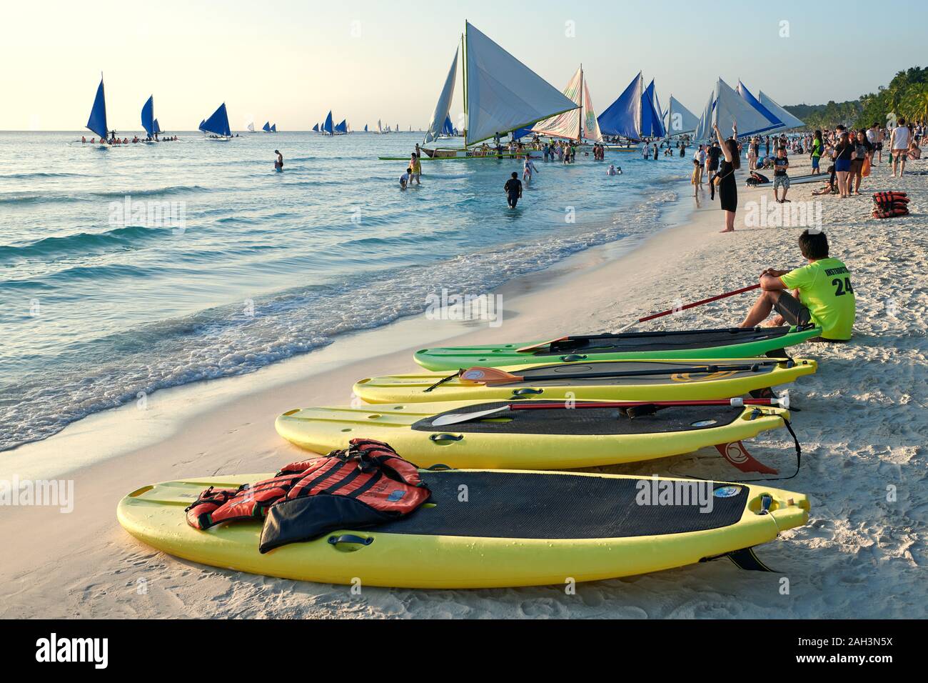 Il Boracay, Aklan Provincia, Filippine - 13 Gennaio 2019: Tramonto alla spiaggia bianca con paddle boards e barche a vela in attesa per i turisti Foto Stock