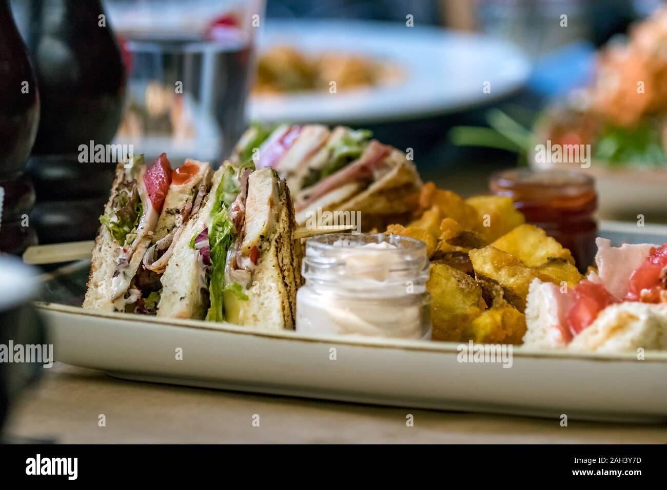 Un club sandwich posto su una piastra con la maionese e patate fritte. Foto Stock