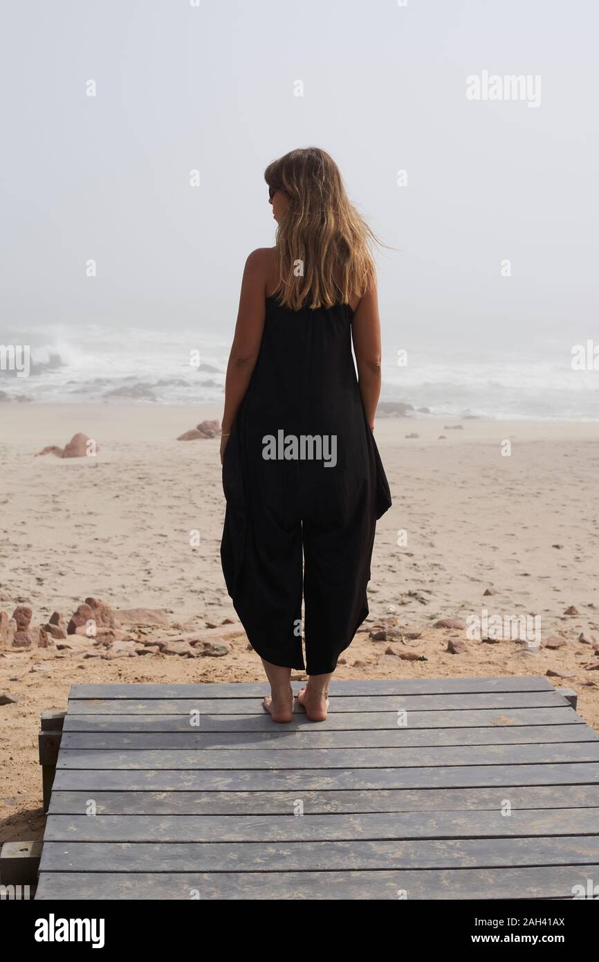 Vista posteriore della donna in piedi sull'oceano, Cape Cross, Namibia Foto Stock