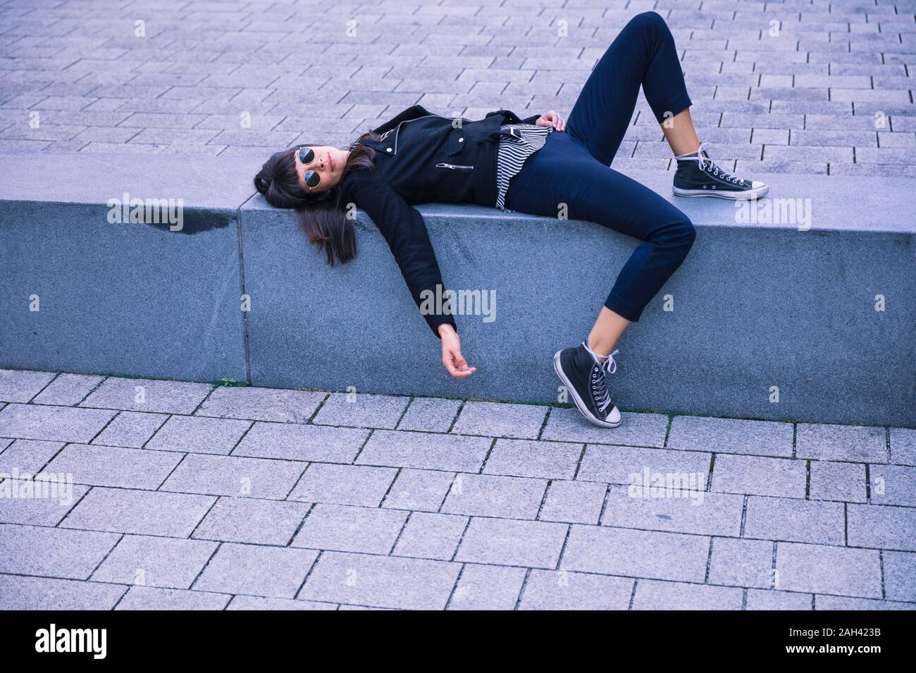 Le donne con occhiali da sole giacente sul banco di calcestruzzo Foto Stock