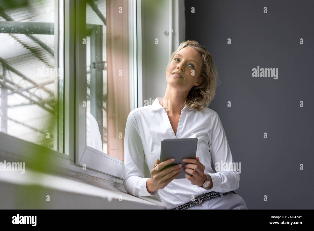 Giovane imprenditrice azienda tablet in corrispondenza della finestra Foto Stock