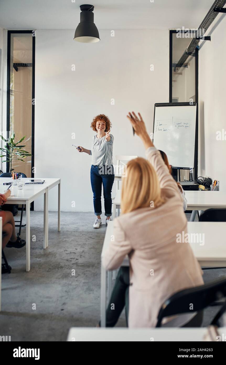 Imprenditrice alzando la mano durante un workshop in sala conferenze Foto Stock
