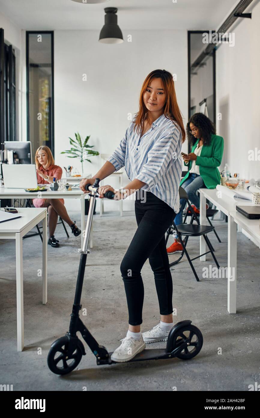 Ritratto di una imprenditrice con kick scooter in office Foto Stock