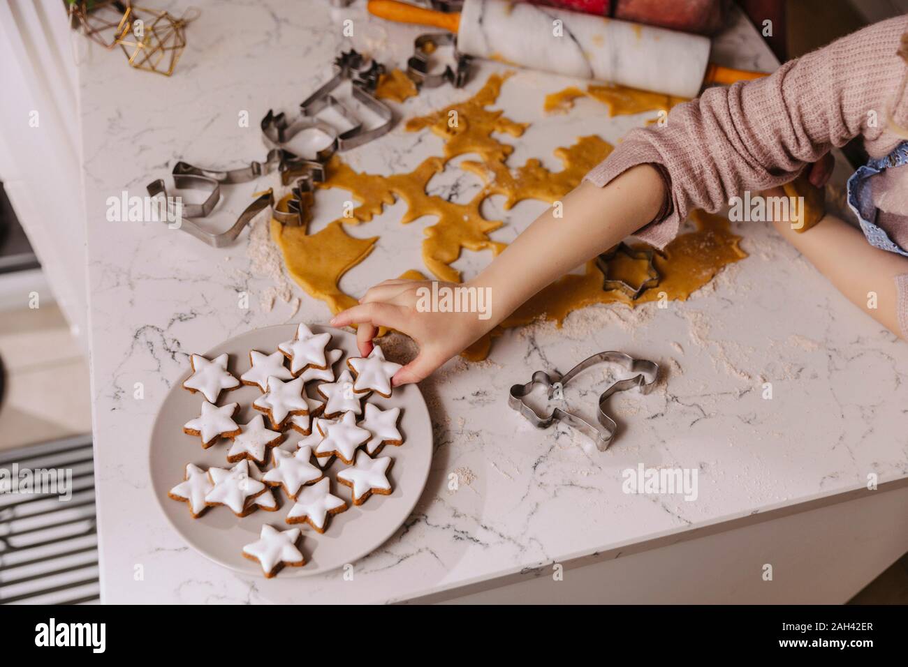 Close-up di ragazza tenendo il Natale cookie dalla piastra su kitchencounter Foto Stock